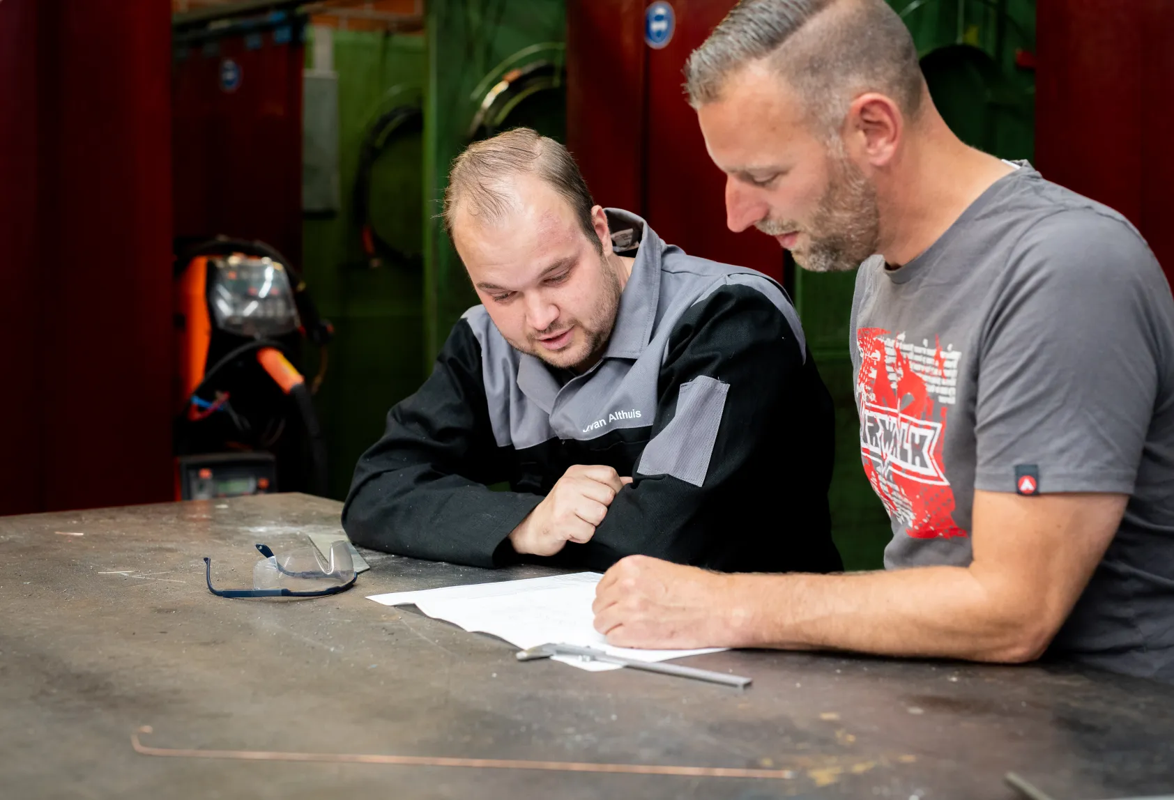 Twee mannen aan een tafel bij een technische tekening
