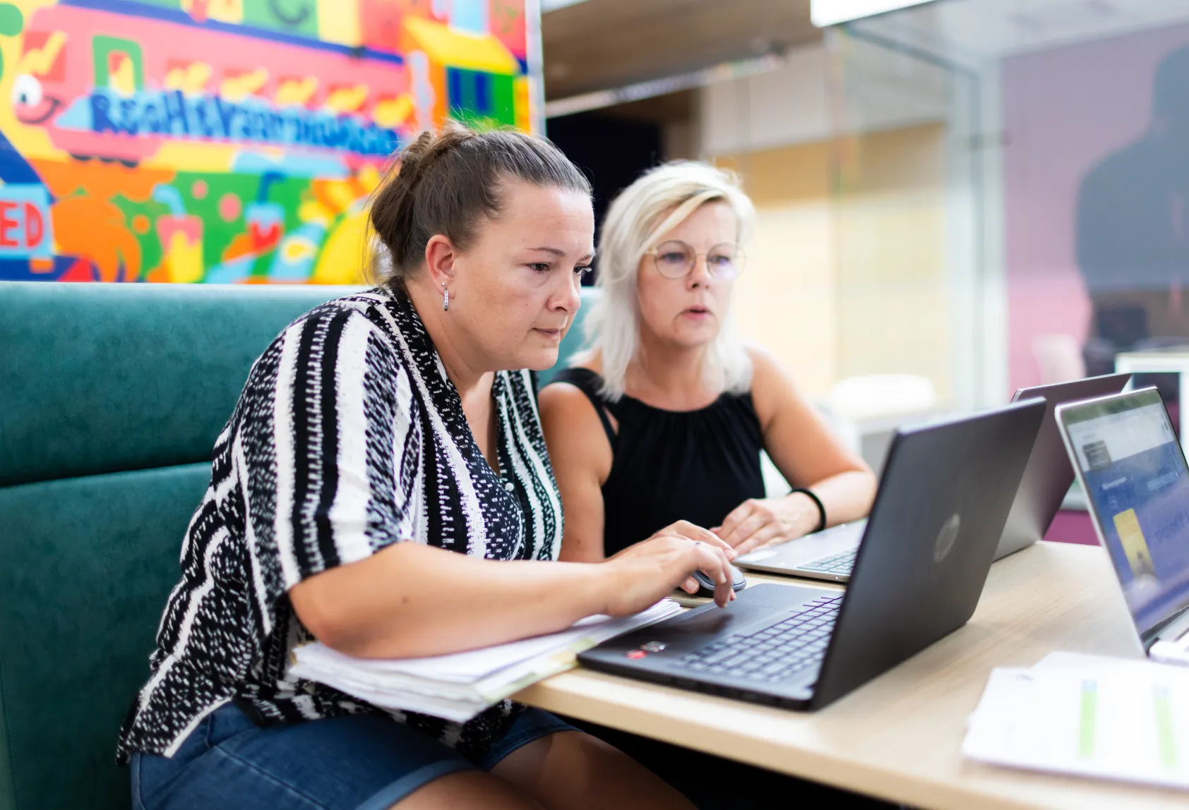 twee vrouwen aan tafel kijken naar een laptop
