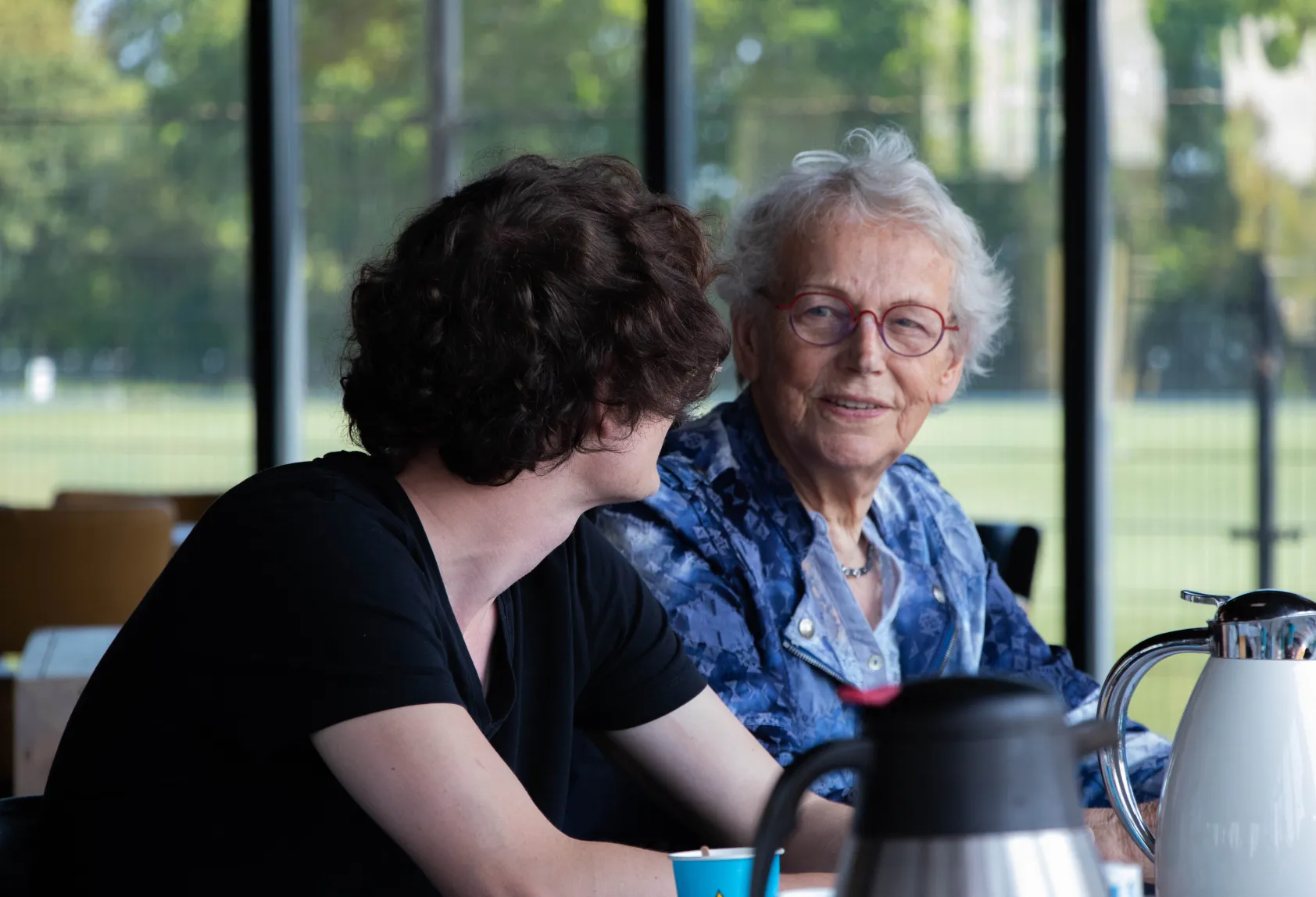 oudere vrouw aan tafel met zorgmedewerker