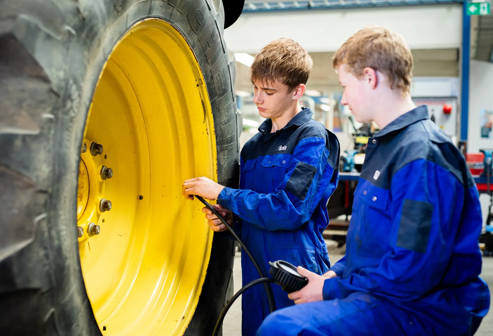 Studenten basistechnicus mobiele werktuigen controleren bandenspanning van een trekker bij Firda