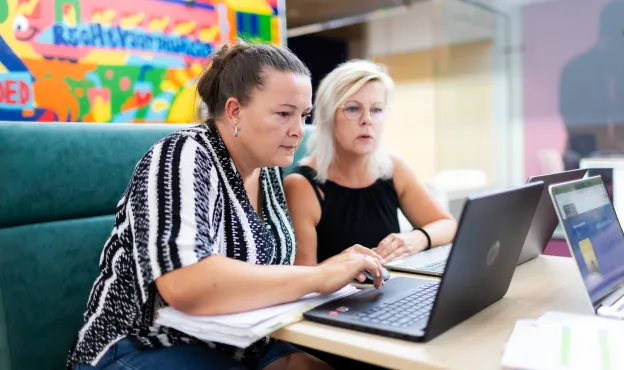 twee vrouwen aan tafel kijken naar een laptop