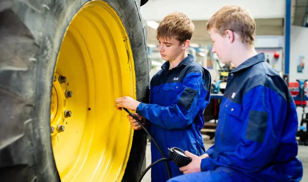 Studenten basistechnicus mobiele werktuigen controleren bandenspanning van een trekker bij Firda
