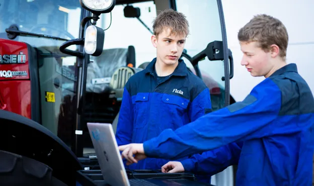 Student technisch specialist mobiele werktuigen leest een mobiel werktuig uit met een laptop en meetapparatuur bij Firda Heerenveen